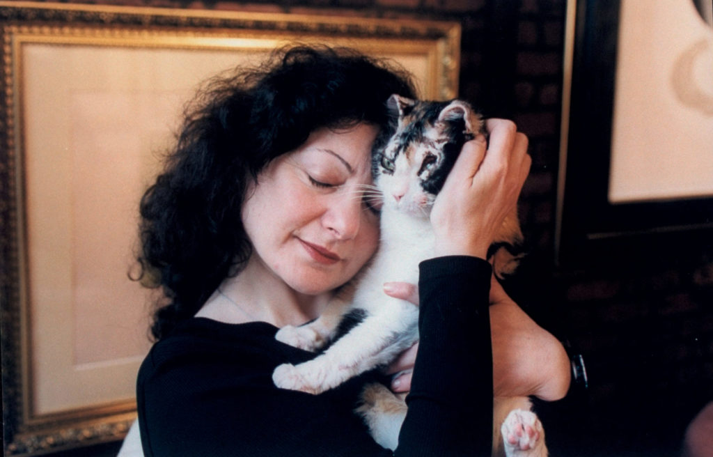 Scarlett the cat, whose eyes were singed shut after saving her kittens during a building fire, snuggled with her new owner, writer Karen Wellen in 1997; Scarlett's eyes healed.